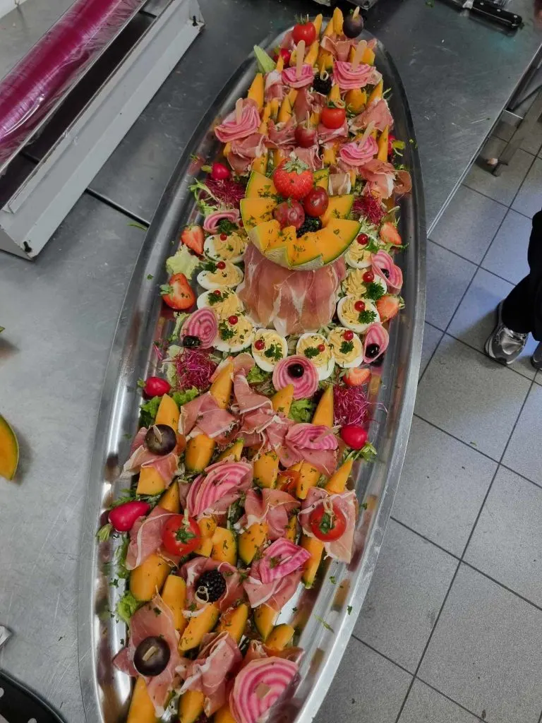 Plat de melon au jambon cru et œufs mimosa, dressé sur plateau inox