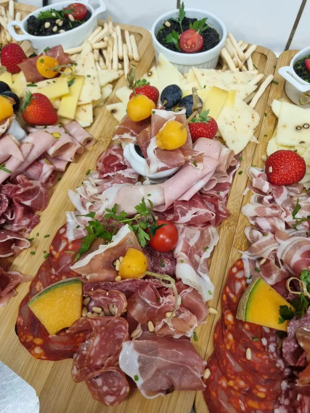 Planches de charcuteries et fromages garnies de melon, fraises et tapenade